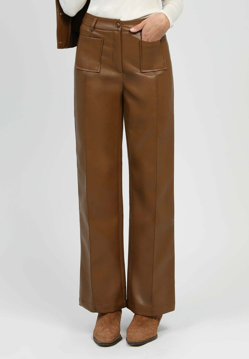 Pantalons large en simili cuir marron avec poches avant et fermeture à bouton, présentant une texture lisse et une forme structurée.