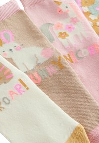 Three pairs of colorful socks featuring animal designs: a unicorn, bunny, and other motifs. Made of soft cotton, with playful text and patterns.