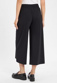 Black culottes with a wide-leg design, elastic waistband, and side pockets. Made from smooth, lightweight fabric. Comfortable fit and modern look.