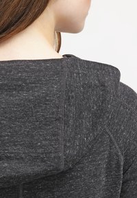 Charcoal gray hoodie featuring a textured fabric, visible seams, and a fitted hood. The back view shows the neckline and shoulder area.