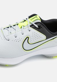 Baltos ir juodos sportinės bateliai su šviesiai pilkais raišteliais, neoninės geltonos spalvos akcentais ir dideliu pilku bei juodu swoosh logotipu šone.