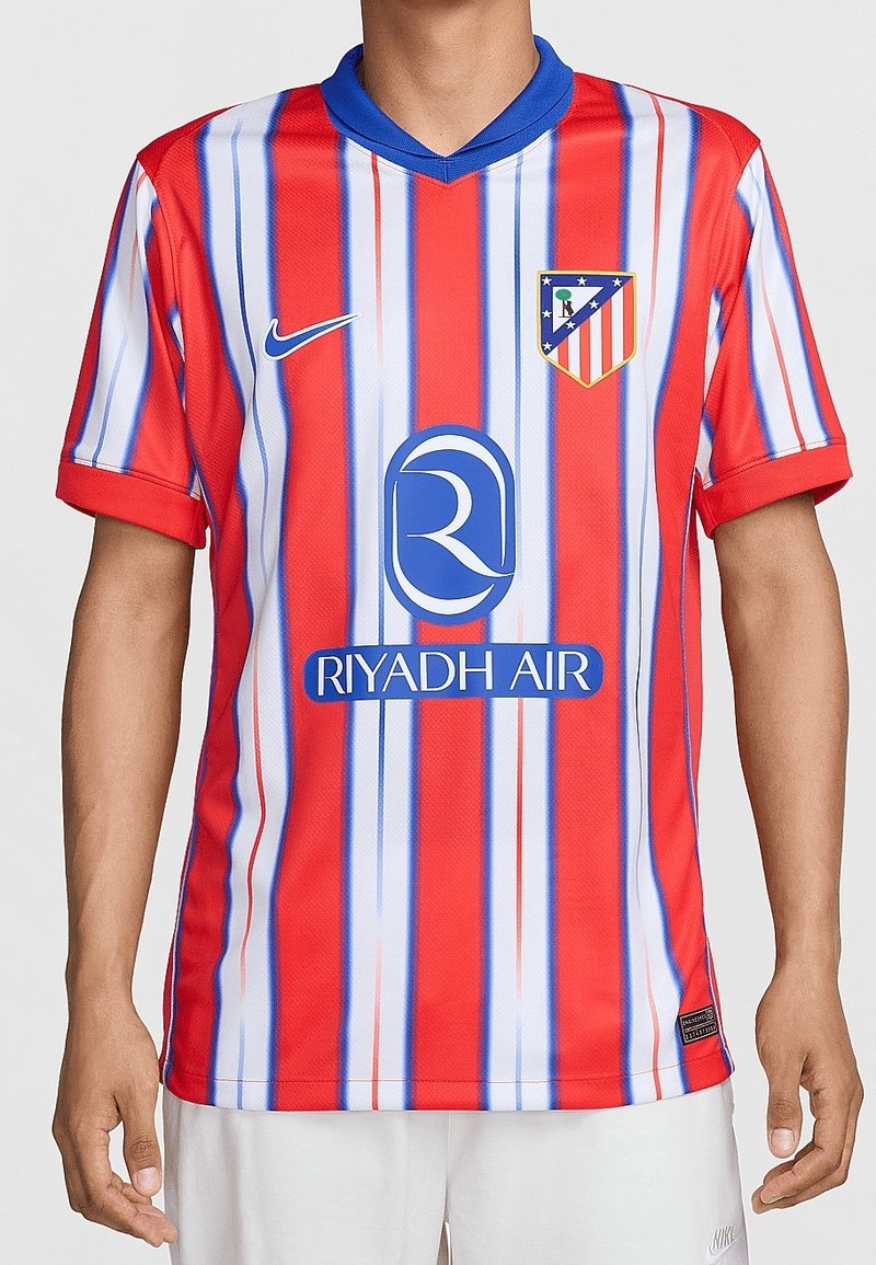 Homme portant un maillot de football Atlético Madrid à rayures rouges, blanches et bleues avec le logo Nike et le logo sponsor Riyadh Air à l'avant.