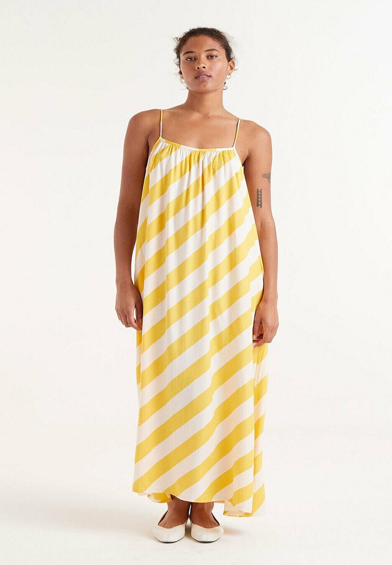 Vestido maxi de rayas amarillas y blancas con tirantes spaghetti, escote fruncido y silueta fluida. Tejido suave con una textura ligera.