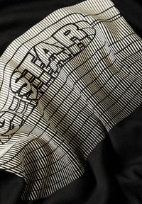 Tela negra con un diseño texturizado y en capas, con patrones lineales blancos y texto en negrita, creando un contraste visualmente impactante.