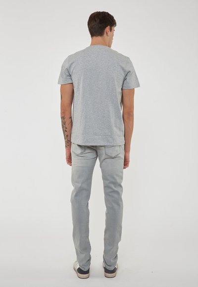 T-shirt in cotone grigio con maniche corte e colletto rotondo, abbinato a jeans in denim grigio chiaro. Design semplice, senza motivi visibili.