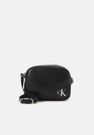 Sac bandoulière rectangulaire noir avec sangle ajustable, boucle argentée et logo blanc "cK" en bas à droite sur le devant.
