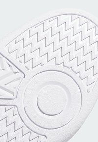 White sneaker sole featuring a textured zigzag pattern with a circular accent, made of rubber, providing grip and durability.