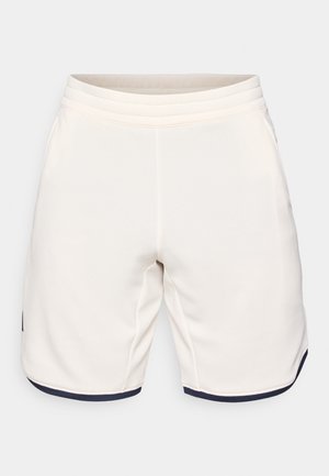 Jasnobeżowe sportowe szorty z teksturowanej tkaniny, z elastycznym pasem i granatowym wykończeniem na dole. Charakteryzują się luźnym krojem i brakiem kieszeni.