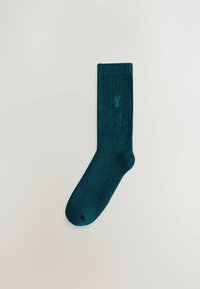 Dark teal ribbed sock made from soft material with a reinforced toe. Features a small logo embroidered near the top.