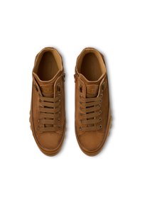Sneakers in suede marrone con punta rotonda, chiusura con lacci e suola in gomma beige. Presentano occhielli in metallo e dettagli cuciti sulla parte superiore.