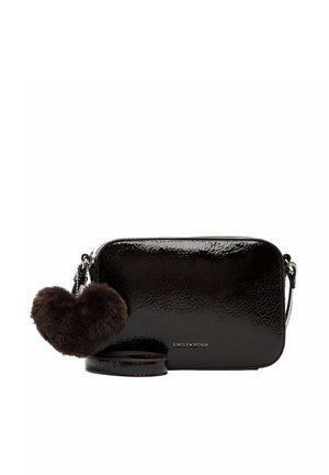 Petit sac bandoulière noir brillant avec un porte-clés peluche en forme de cœur et une bandoulière amovible sur fond blanc.