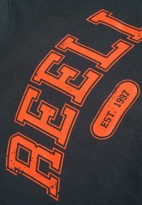 Tela negra con un gran y audaz texto naranja "REBEL" y un pequeño óvalo naranja que contiene "EST. 1997" en letras negras.