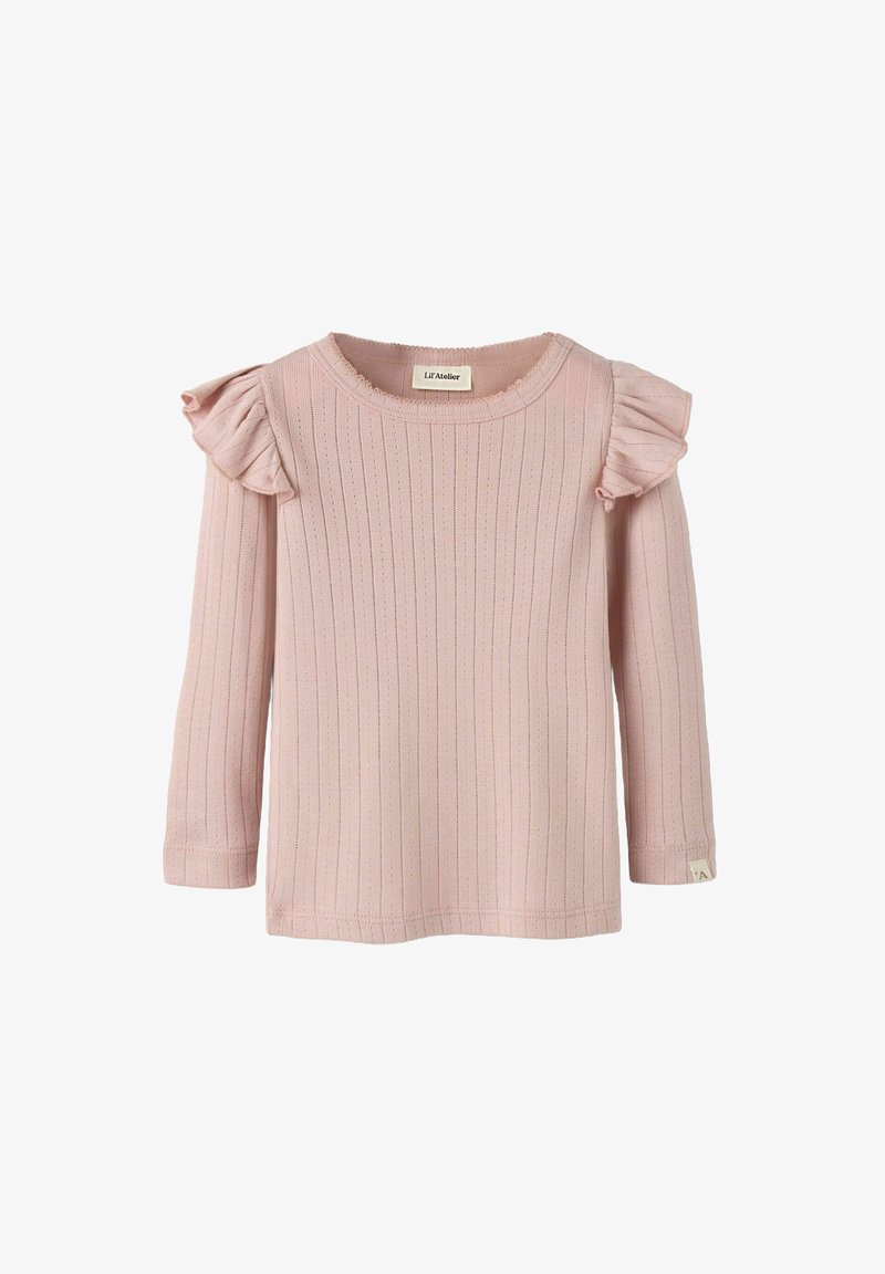 Chemise à manches longues rose pâle avec texture côtelée, accents à volants sur les épaules et col rond. Une étiquette sur le côté inférieur ajoute un détail.