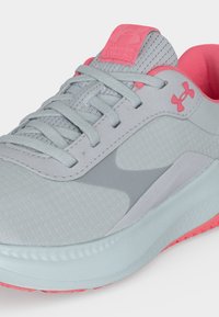 Ανοιχτού γκρι και ροζ παπούτσι τρεξίματος Under Armour με αεριζόμενο επάνω μέρος, κορδόνια και μαλακή σόλα.