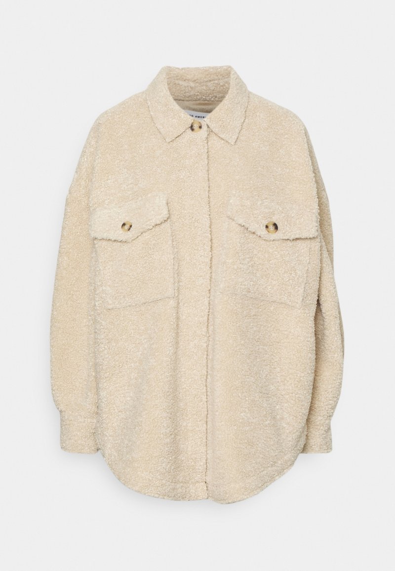 Beige Fleece-Übershirt mit Kragen, zwei Brusttaschen und goldfarbener Knopfverzierung. Weicher Stoff und lockere Passform. Runde Saumlinie.