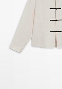 Off-white langærmet jakke med tre sorte frølukninger ned foran og en lige kant.