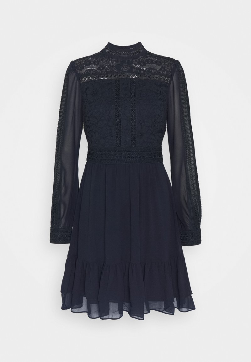 Robe noire à manches longues avec corsage en dentelle, manches transparentes, col montant, détails à la taille et ourlet volanté sur un fond uni.