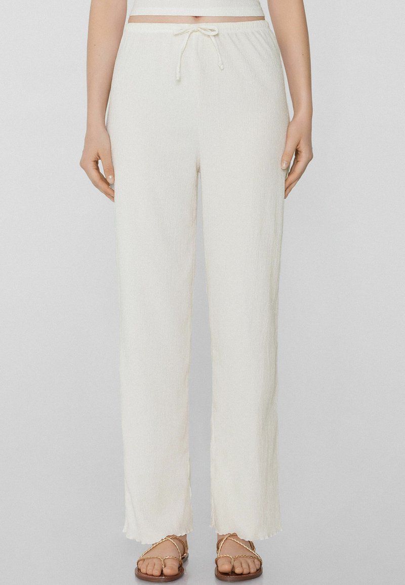 Pantaloni ampi bianchi, texture, con vita elasticizzata e coulisse. Presentano orli grezzi e una vestibilità comoda.