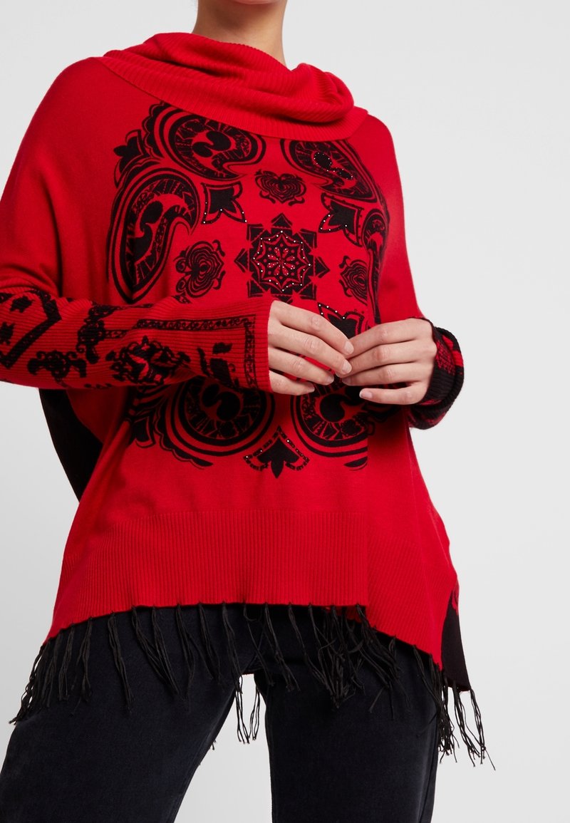 Rode trui met een col en zwart geborduurde patronen. Voorzien van een franjeszoom en geribbelde boorden. Gemaakt van zacht gebreid materiaal.