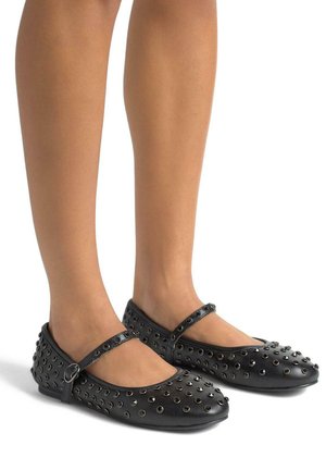 Mocasines negros tipo Mary Jane de cuero, con punta redondeada, una correa con hebilla y textura con tachuelas a lo largo de los lados.