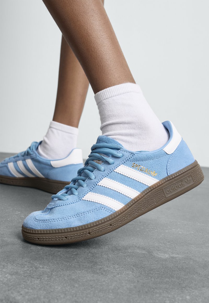 Modri semiš copati s belimi črtami in detajli, z teksturirano rjavo gumijasto podplatom in zlatim logotipom "Spezial".