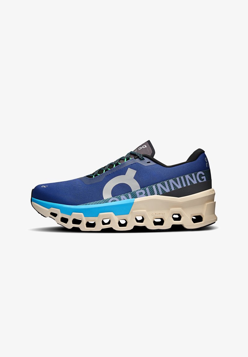 Running shoe with a blue mesh upper, black accents, large logo, and a distinctive cream-colored sole featuring hexagonal cutouts.