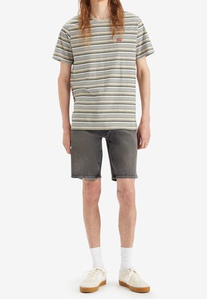 Striped short-sleeve t-shirt in cream, green, and gray; black denim shorts; white socks; beige sneakers with brown soles.