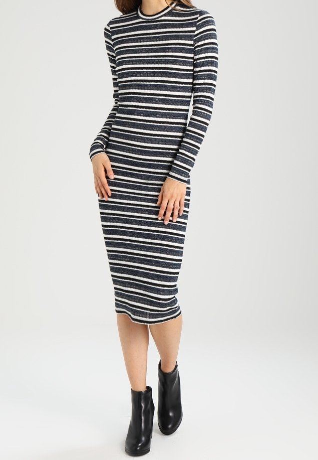 Robe à manches longues et ajustée avec des rayures horizontales bleu marine et blanches, dotée d'un col rond et d'une texture côtelée. Portée avec des bottines noires à la cheville.