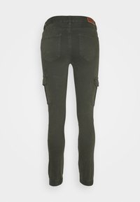 Mörkgröna cargo-byxor med elastiska ankle-cuffs, fem fickor inklusive två sidofickor, och en brun läderlogotyp på midjan.