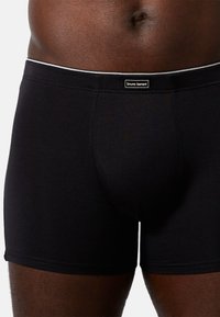 Boxer neri realizzati in tessuto morbido con un design aderente, con un accento bianco sulla vita e una piccola etichetta del marchio.