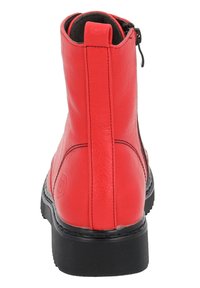 Stivaletto in pelle rossa con una superficie liscia, suola in gomma nera e chiusura con zip laterale. Presenta una punta arrotondata e dettagli di cucitura minimal.