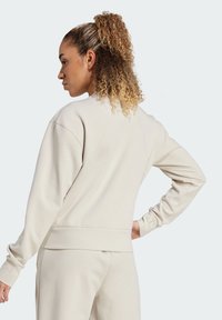 Beiger Sweatshirt mit langen Ärmeln, gerippten Bündchen und Saum. Verfügt über einen Rundhalsausschnitt und eine glatte Stofftextur. Die Rückansicht zeigt die Schulternähte.