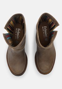 Botas de cuero marrón hasta el tobillo con punta redonda y detalles de costura. El interior cuenta con un forro a rayas multicolor.
