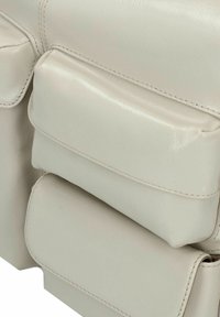 Leren tas in lichtgrijs met een gladde textuur. Bevat meerdere rechthoekige vakken en contrasterende stiksels voor extra detail.
