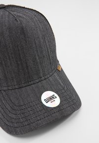 Cappello in denim nero con visiera strutturata, caratterizzato da un adesivo circolare con la scritta "DJINNS ESTD 2004" in bianco e colori iridescenti.