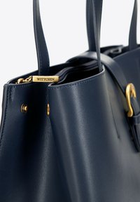 Granatowa skórzana torebka z złotymi akcentami, z metką z napisem "WITTCHEN" i gładkim, zdefiniowanym designem.