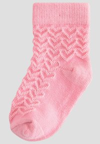 Chaussette rose à la cheville présentant un motif en zigzag texturé sur la partie supérieure, avec une section inférieure lisse. Fabriquée en matériau doux et tricoté.