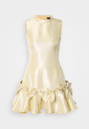 Krátke bezrukávové šaty z lesklého svetlozlatého materiálu. Obsahujú imitovaný golier, priliehavý korzet a rozšírenú sukňu s mašľovými ozdobami na leme.