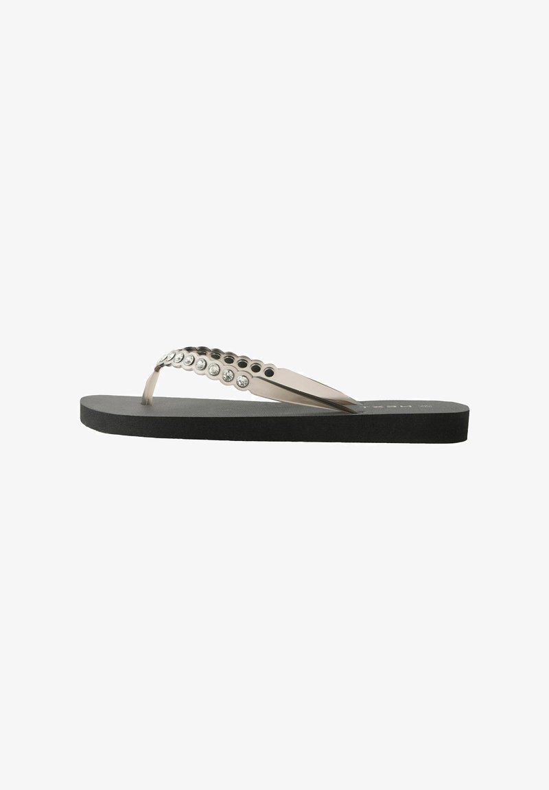 Flip-flops ar melnu gumijas zoli, caurspīdīgām siksnām, rotātām ar sudraba kniedēm, un gludu teksturētu kāju gultni.