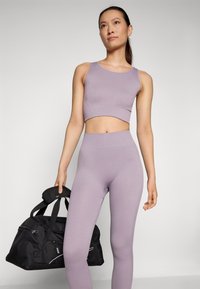 Lilac ribbed crop top and high-waisted leggings, paired with a black gym bag featuring zippers and padded handles.