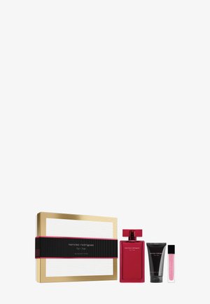 Set de regalo con caja bordeada de oro, botella de perfume roja, tubo negro y pequeño brillo de labios rosa, todos etiquetados "narciso rodriguez for her."