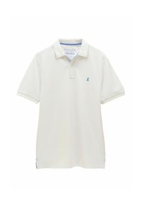 Balta polo krekls ar īsām piedurknēm, izgatavots no teksturētas auduma. Tam ir zils logo uz krūtīm un gaiši zili akcenti uz apkakles.