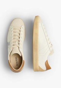 Cream-colored sneakers with suede and leather upper, textured gum sole, lace-up design, and brown accents at the heel.