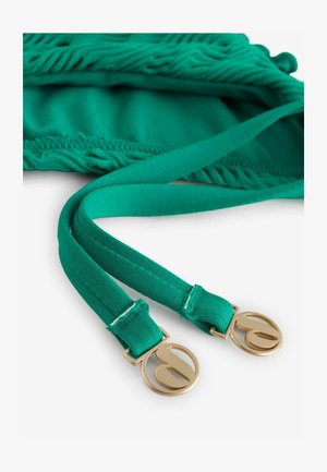 Curea din țesătură culoarea teal, cu capete cu textură nervurată, prevăzute cu catarame rotunde din metal auriu cu design decupat, așezată pe un material țesut asortat.