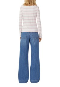 Long-sleeve ribbed top in light pink with white stripes paired with wide-leg blue denim jeans, featuring back pockets and a relaxed fit.