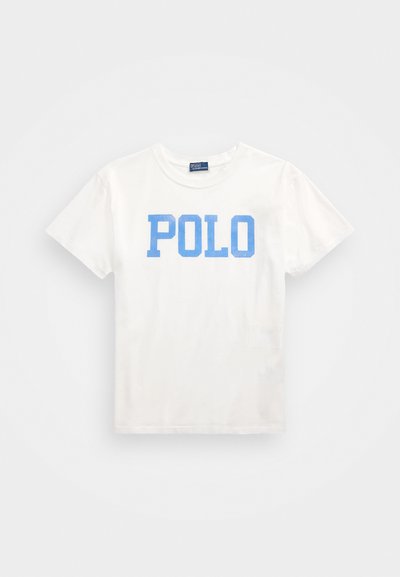 Bela bombažna majica s kratkimi rokavi, ki na sprednji strani vsebuje velik modri napis "POLO". Klasična zasnova s krožnim ovratnikom.
