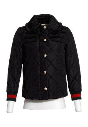 Veste matelassée noire avec col à volants, boutons dorés sur le devant, et poignets côtelés rayés vert-rouge sur les manches longues.
