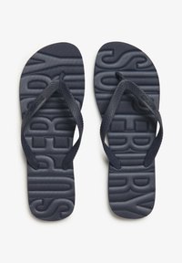 Tongs navy bleues avec une semelle texturée, présentant un logo en relief et des brides à motif chevrons pour l'adhérence et la durabilité.