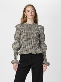 Svart-og-hvitt rutete bluse med smocked halslinning og skuldersømmer, volang mansjetter og peplum i hemmen, kombinert med svarte bukser.