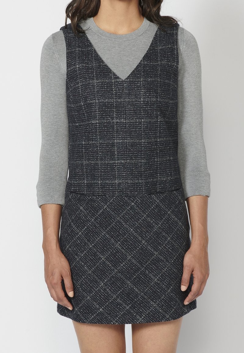 Navy plaid dress in a textured fabric, layered over a light gray long-sleeve top with a round neckline. Features a fitted bodice and flared skirt.